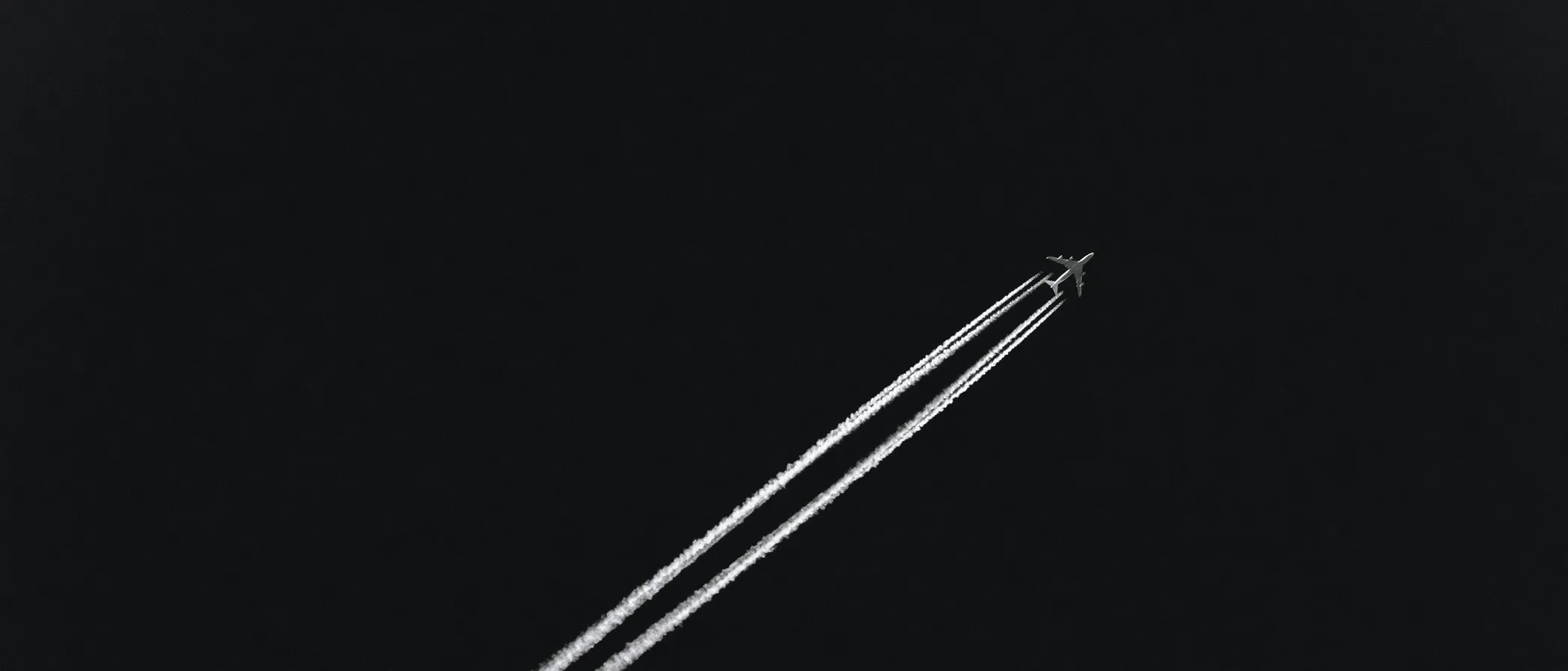 Kondensstreifen eines Flugzeugs am schwarzen Himmel