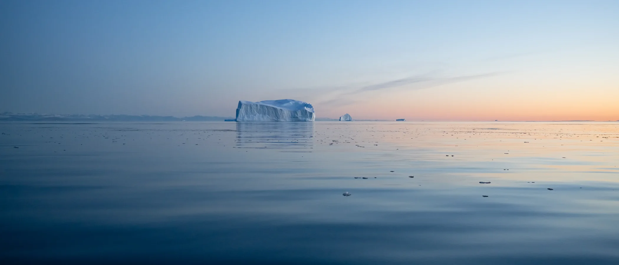 Eisberg im Morgenlicht auf spiegelglattem Wasser